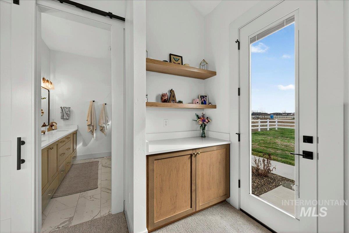 24853 Haflinger Way Middleton, ID 83644 - Photo 31 of 49 Bar with light countertops, wood finish cabinetry, a barn door, open shelves, and light marble finish flooring