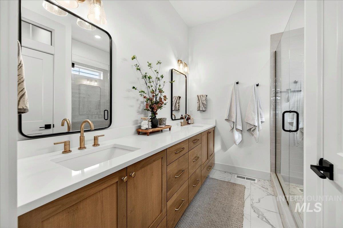 24853 Haflinger Way Middleton, ID 83644 - Photo 32 of 49 Full bathroom with double vanity, a shower stall, and light marble finish flooring