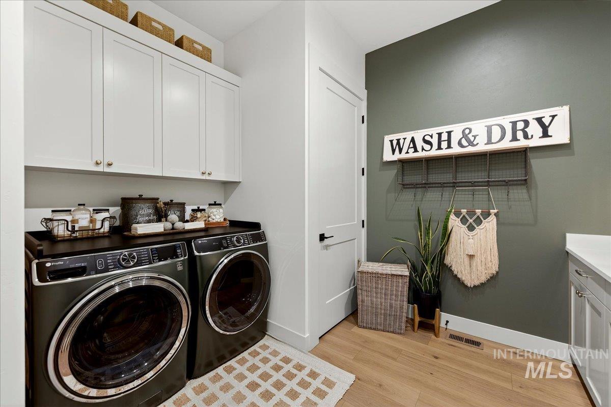 24853 Haflinger Way Middleton, ID 83644 - Photo 37 of 49 Laundry room with cabinet space, washing machine and clothes dryer, and light wood-style flooring