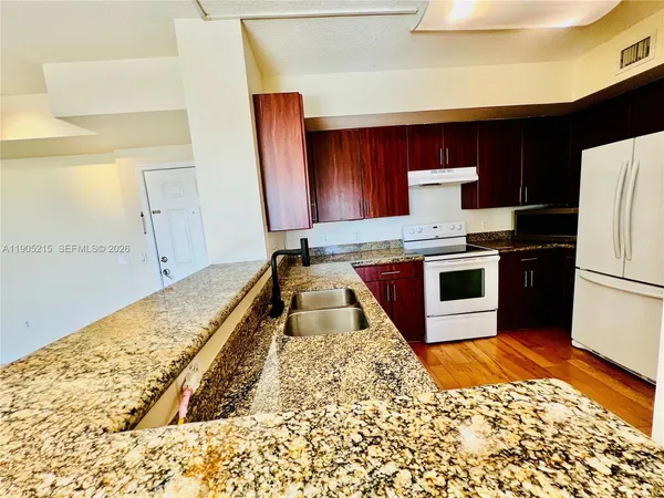 a kitchen with stainless steel appliances granite countertop a stove a sink and a refrigerator