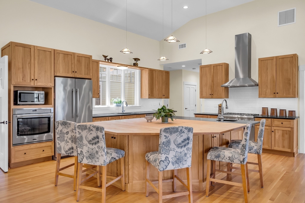 17 Whitney Road Stow, MA 01775 - Photo 13 of 42 a kitchen with granite countertop a refrigerator stove a sink a dining table and chairs with wooden floor