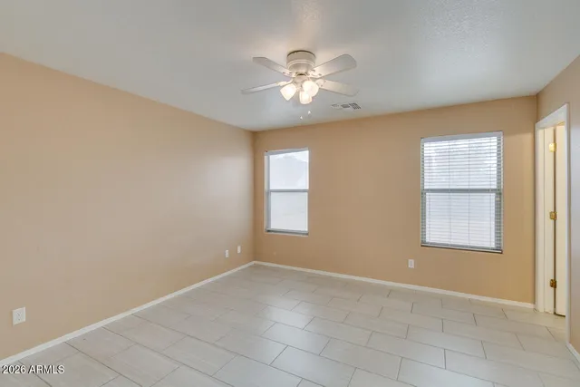an empty room with chandelier fan and windows