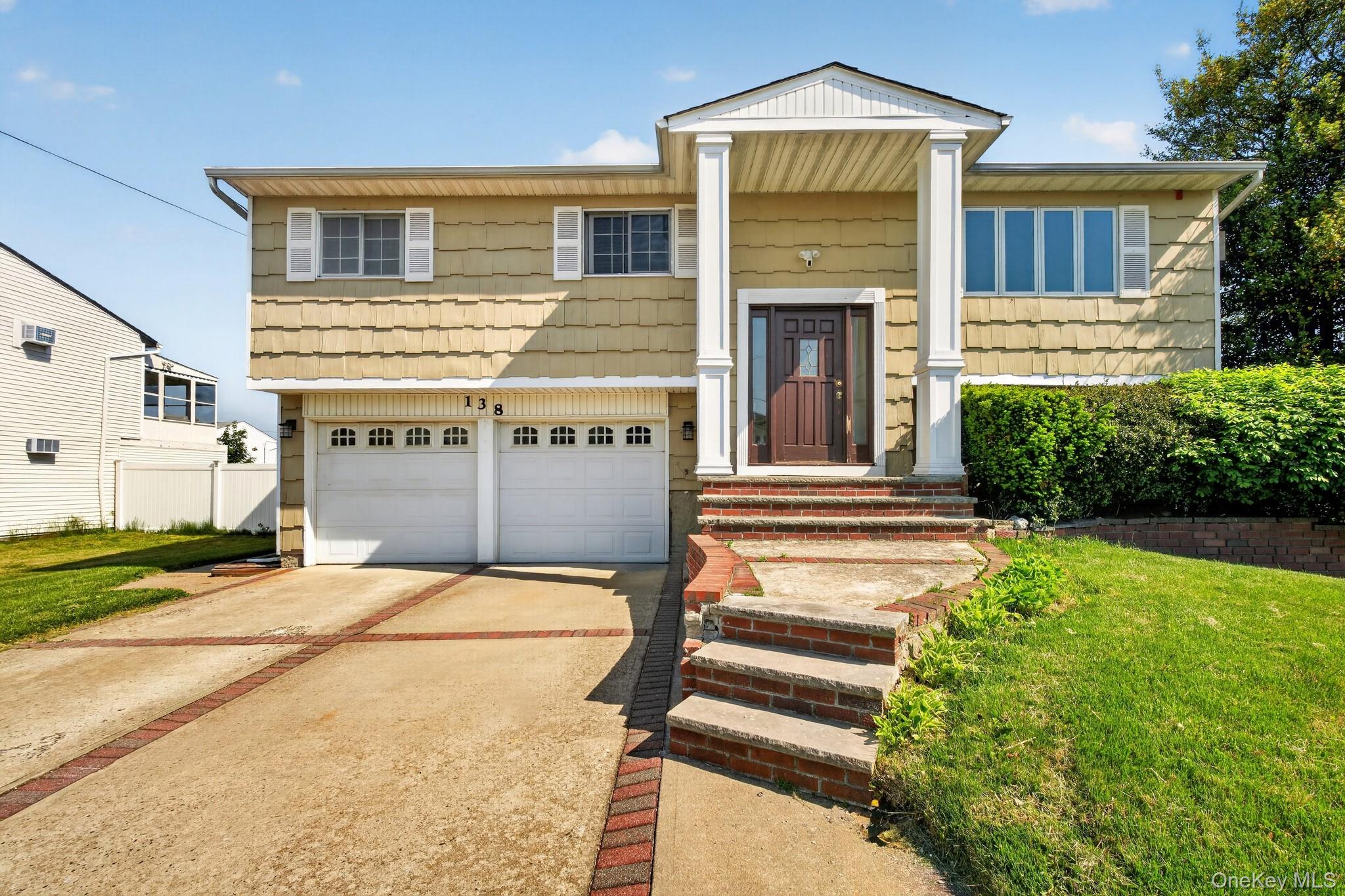 138 Spring Street Massapequa, NY 11758 - Photo 2 of 45 a front view of a house with a garden and garage
