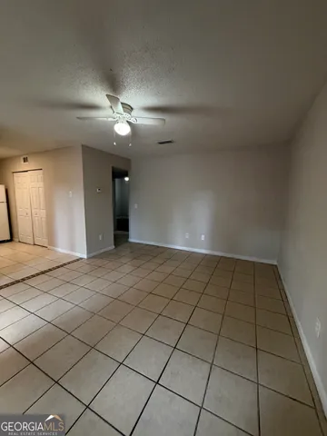 a view of an empty room and chandelier fan