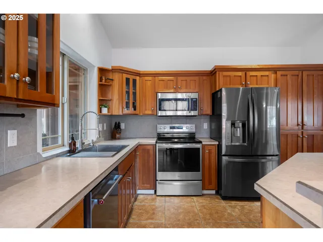 a kitchen with stainless steel appliances granite countertop a refrigerator a sink a stove and island