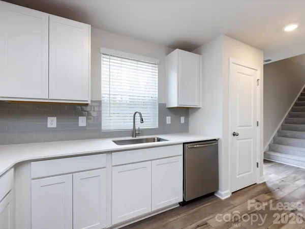a kitchen with stainless steel appliances granite countertop white cabinets a sink and dishwasher with wooden floor