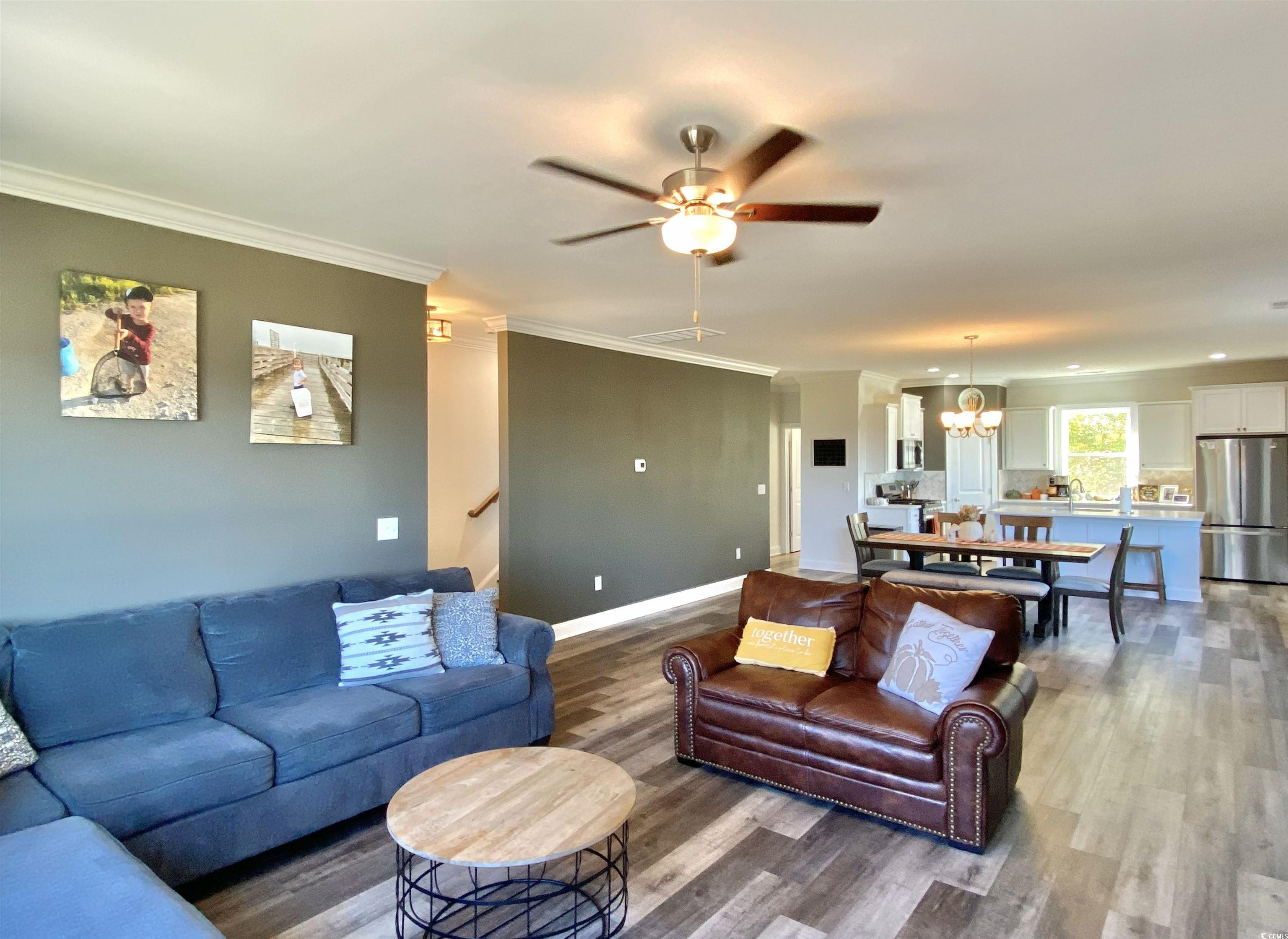 2664 Seaport Circle Georgetown, SC 29440 - Photo 16 of 40 Living room featuring crown molding, light wood-style floors, ceiling fan, and a chandelier