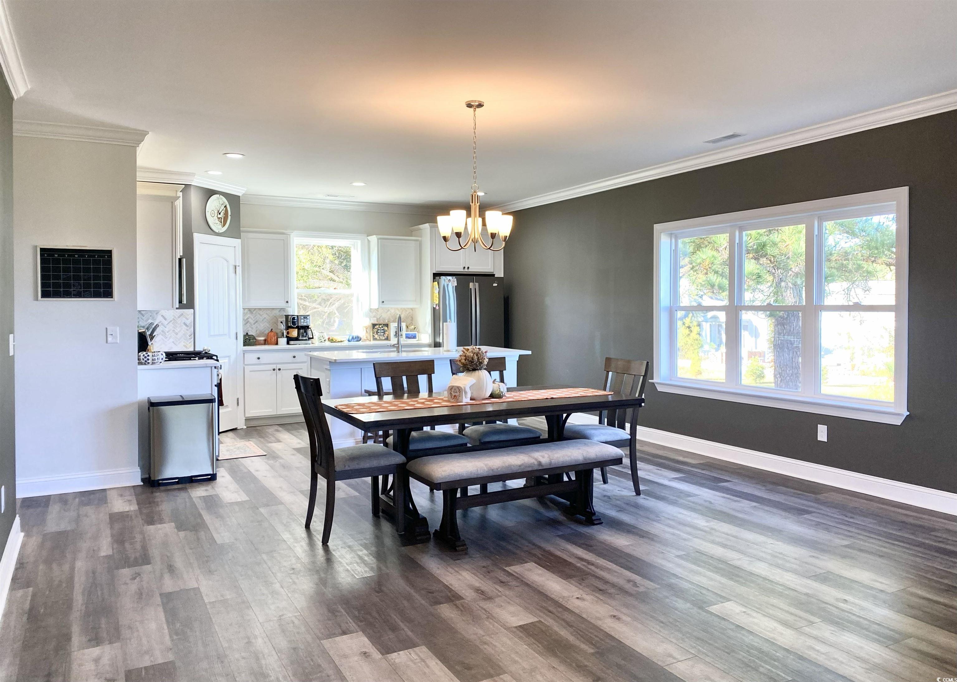 2664 Seaport Circle Georgetown, SC 29440 - Photo 9 of 40 Dining space featuring ornamental molding, dark wood-style flooring, and a chandelier