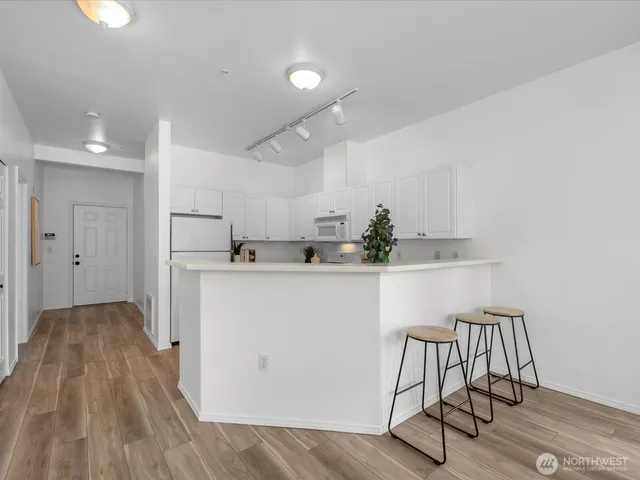a kitchen with a sink dishwasher stove and white cabinets with wooden floor