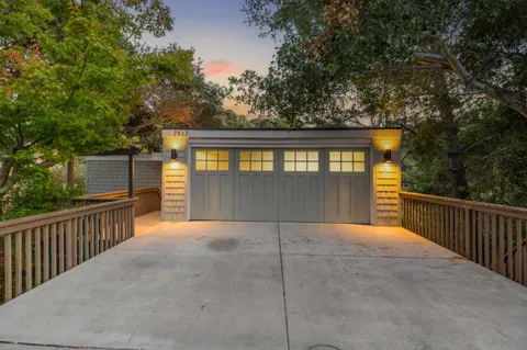 a view of backyard with large trees and wooden fence