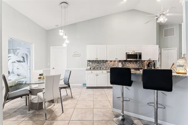 a kitchen with stainless steel appliances kitchen island granite countertop a dining table chairs and a refrigerator