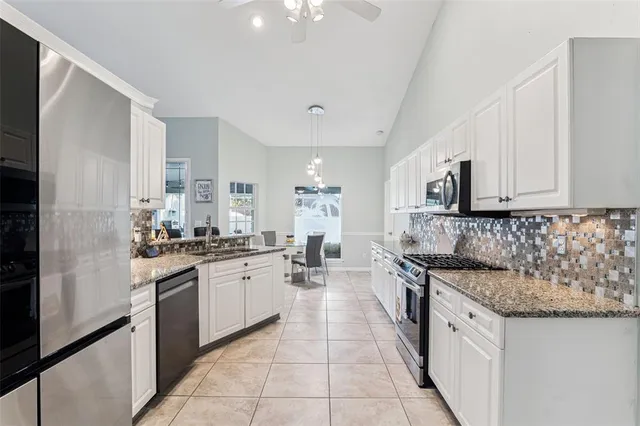 a large kitchen with granite countertop a sink and cabinets
