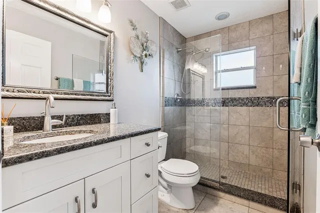 a bathroom with a granite countertop sink a toilet and a mirror