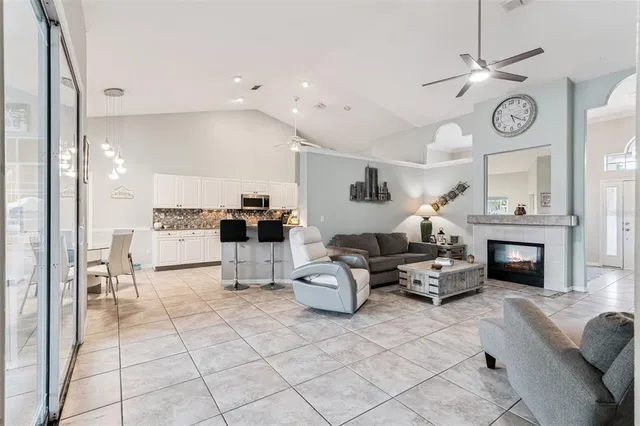 a living room with furniture a clock and a view of kitchen