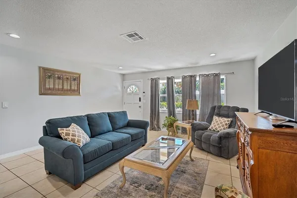 a living room with furniture a flat screen tv and a window