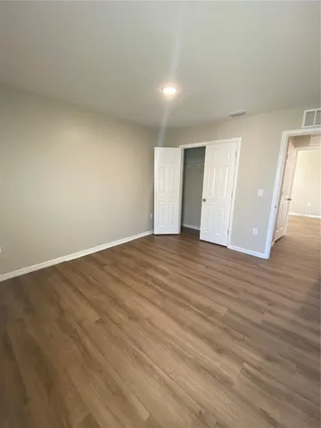 a view of an empty room with wooden floor and entryway