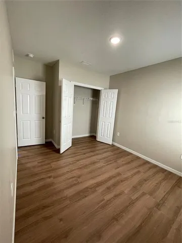a view of an empty room with wooden floor and closet