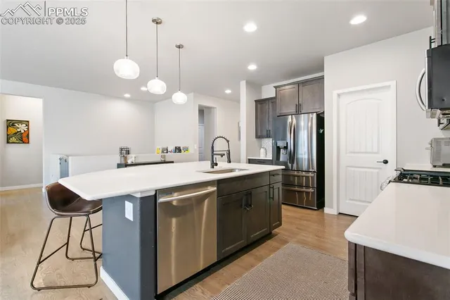 a large kitchen with stainless steel appliances a stove a refrigerator a oven a sink with a dining table and chairs