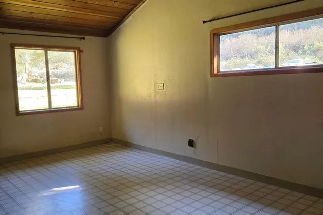 an empty room with wooden floor a fireplace and windows