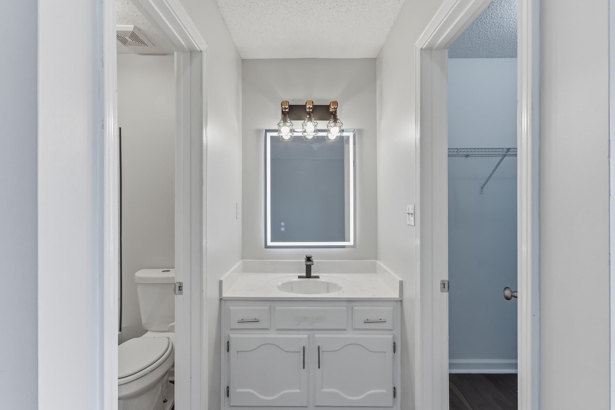 4101 Long Creek Road Memphis, TN 38125 - Photo 19 of 36 Vanity area featuring a quartz countertop, white cabinetry with silver-tone hardware, and a modern illuminated mirror