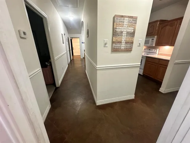 a view of a hallway with wooden floor and electronic appliances