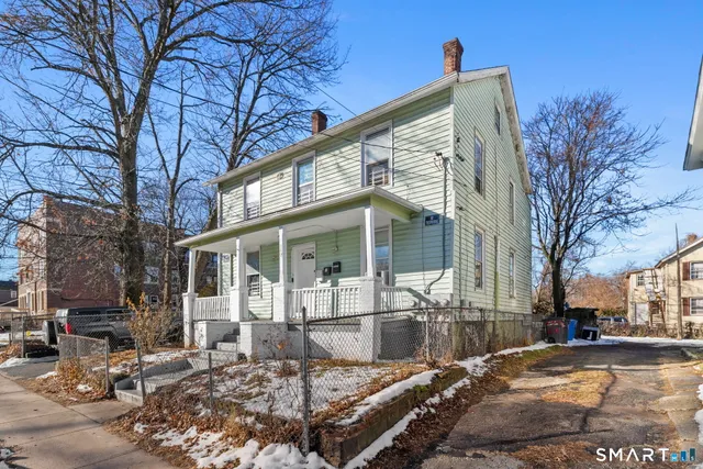 a view of a white house with a large tree