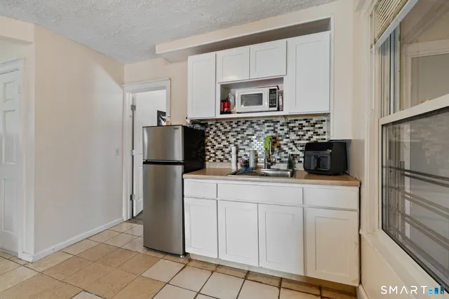 a kitchen with white cabinets and refrigerator