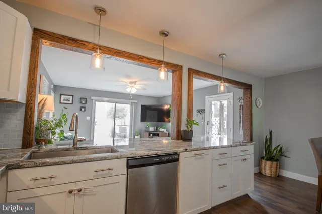 a open kitchen with granite countertop a sink and white cabinets with wooden floor