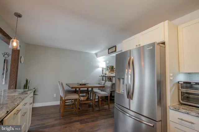 a kitchen with stainless steel appliances a refrigerator a stove a dining table and chairs with wooden floor