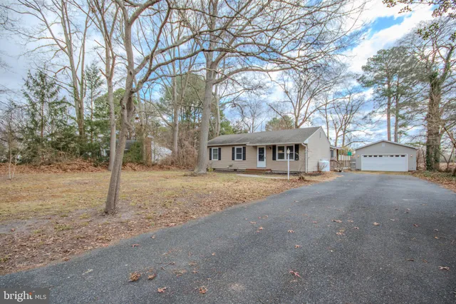 a front view of a house with a yard and large trees