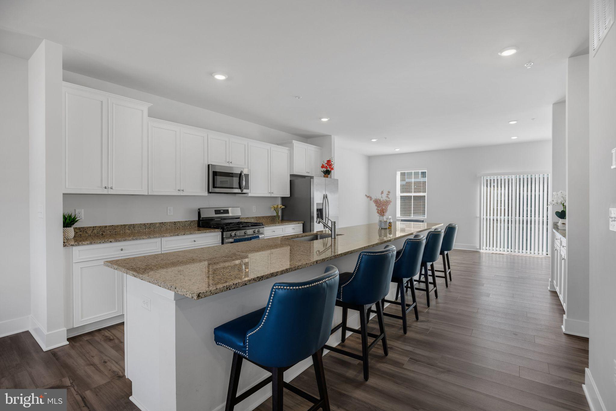 4165 Brodie Place White Plains, MD 20695 - Photo 2 of 28 a kitchen with stainless steel appliances granite countertop a stove a sink a microwave a dining table and chairs with wooden floor