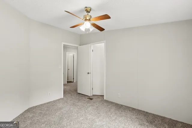 an empty room with a window and a fan