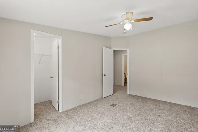 an empty room with ceiling fan and window