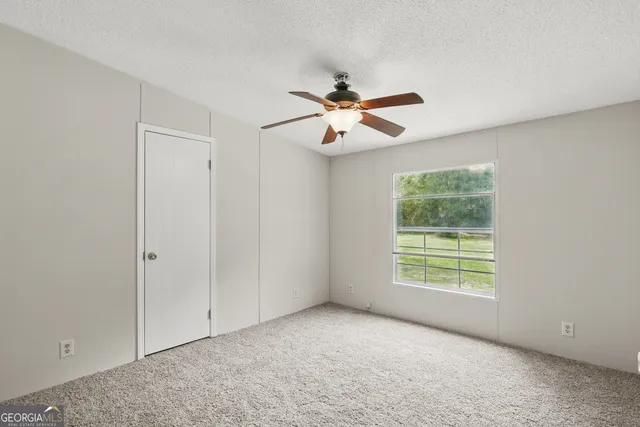 an empty room with windows and fan