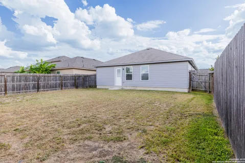 a view of a house with backyard and wooden fence