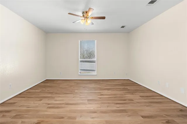 a view of an empty room with a window and a chandelier fan