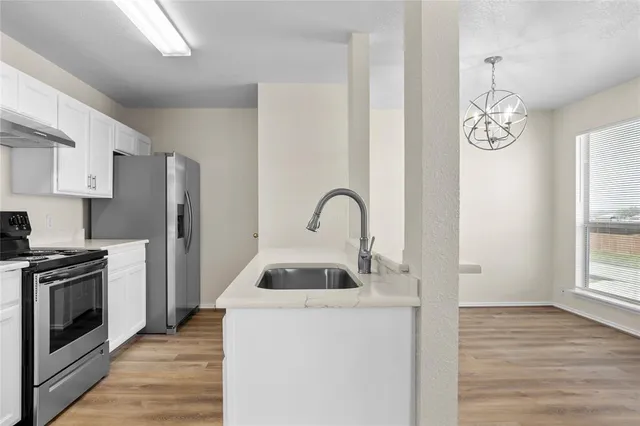 a kitchen with granite countertop a sink stainless steel appliances and window