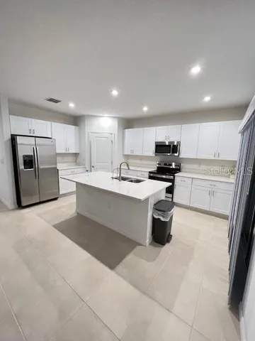 a large kitchen with stainless steel appliances kitchen island a sink a stove a microwave a center island and cabinets