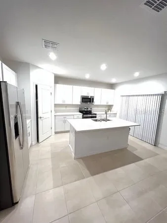 a large kitchen with stainless steel appliances kitchen island granite countertop a refrigerator a stove a sink and a granite counter tops