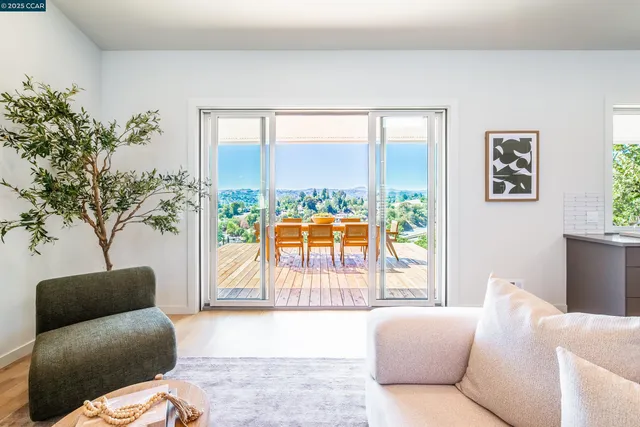 a living room with furniture kitchen view and a large window