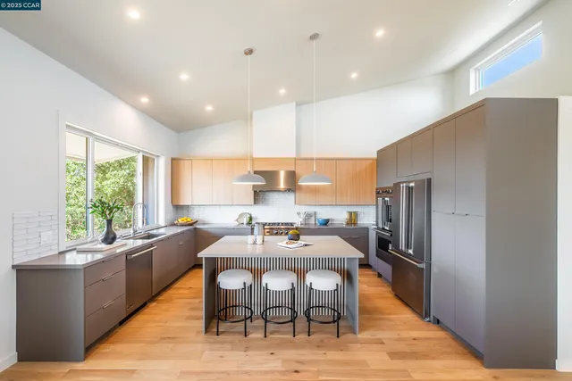a kitchen with a refrigerator a sink a stove and a dining table with wooden floor