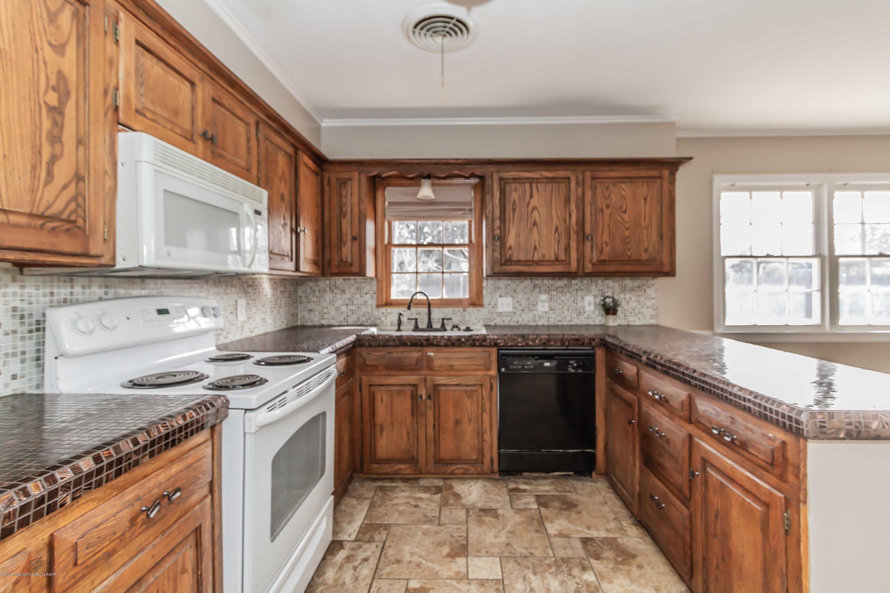 6205 Calumet Road Amarillo, TX 79106 - Photo 6 of 39 a kitchen with stainless steel appliances granite countertop a sink stove cabinets and a window