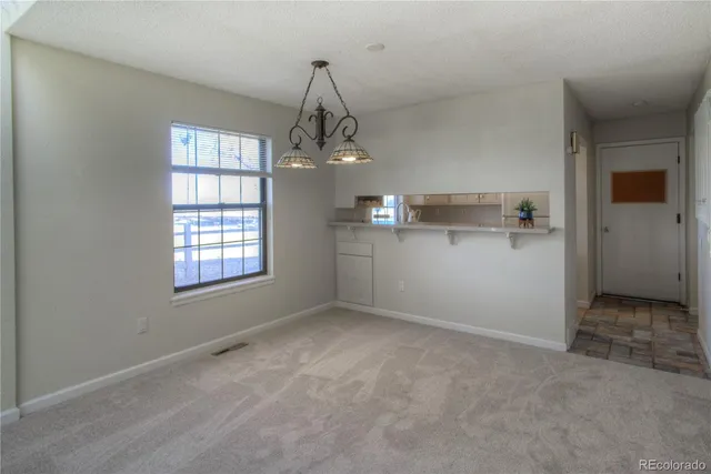 an empty room with windows and chandelier fan