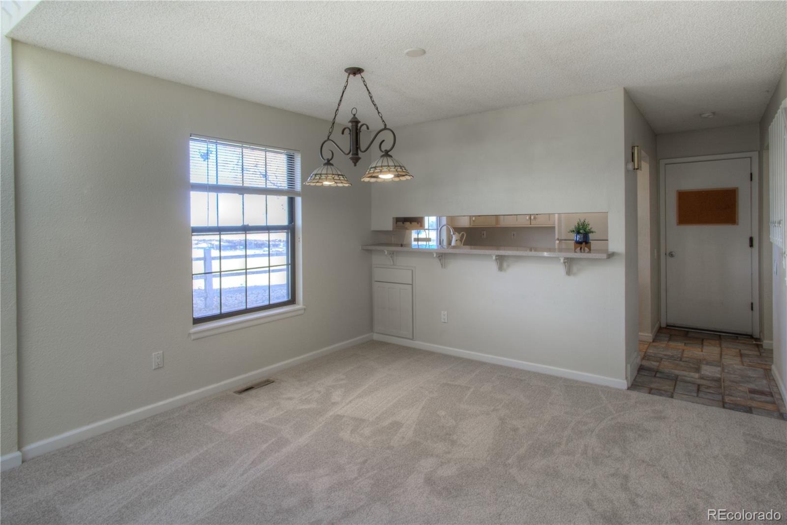 11781 West Elk Head Range Road Littleton, CO 80127 - Photo 9 of 48 an empty room with windows and chandelier fan