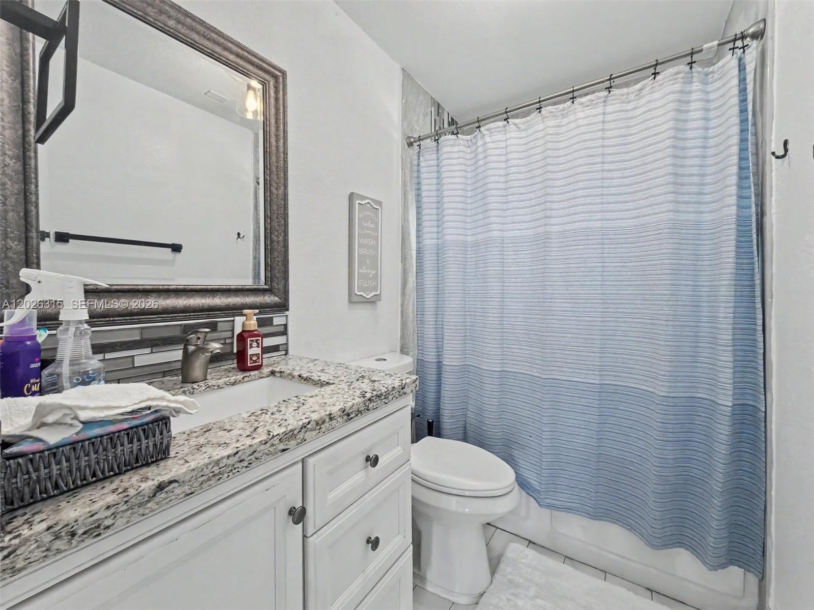 10762 Southwest 145th Street Miami, FL 33176 - Photo 11 of 28 a bathroom with a granite countertop sink mirror vanity and toilet