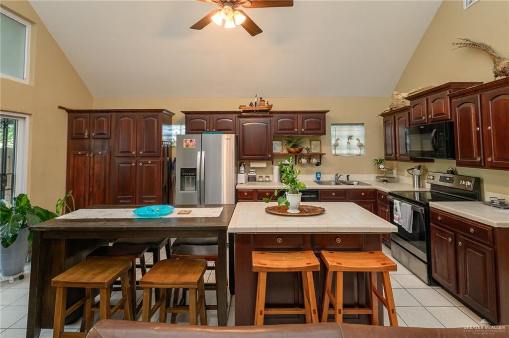 36431 Marshall Hutts Road Rio Hondo, TX 78583 - Photo 8 of 45 a kitchen with stainless steel appliances kitchen island granite countertop a table chairs and a refrigerator