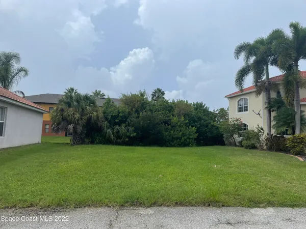 a front view of a house with a yard and palm trees
