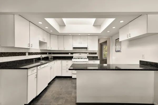 a large kitchen with granite countertop a sink and white stainless steel appliances