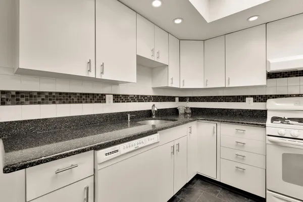 a kitchen with granite countertop white cabinets and white appliances