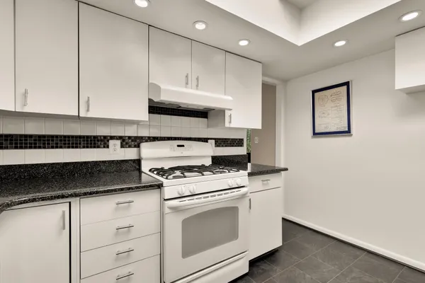 a kitchen with granite countertop white cabinets and white appliances